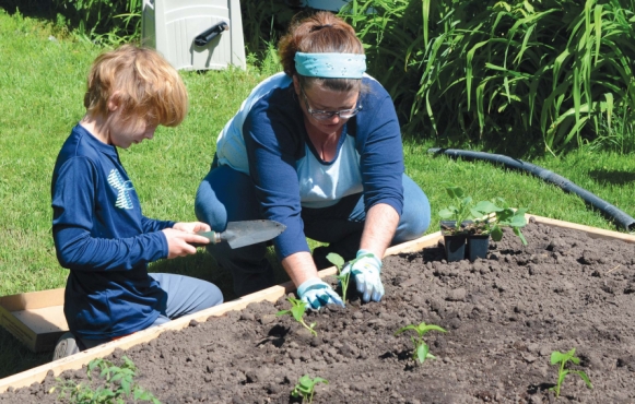 Kelly Brinker and her son, Jack, plant a Victory Garden 2.0 in a Green Bay Garden Blitz raised garden. – Photo by Rick Cohler